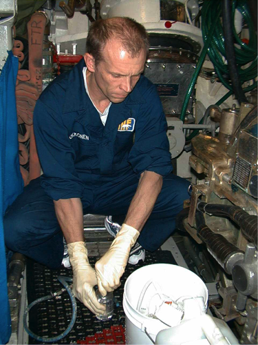 Figure 2: Oceanographer, Steve Okkonen, fills water bottles with sea water using a through-hull valve in the submarine&#39;s torpedo room. Image courtesy of U.S. Navy Arctic Submarine Laboratory.