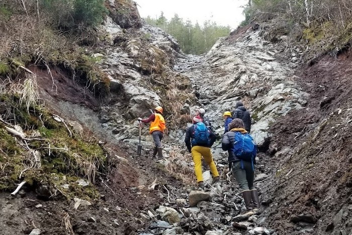 U.S. Forest Service Soil Scientist Jacquie Foss gives a description of layers of volcanic ash exposed in a debris flow channel. Photo courtesy of the Sitka Sound Science Center.