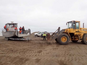 Heavy equipment being used to launch a boat big enough for large waves but too big for the boat ramp when the water is low at Utqiaġvik, Alaska 
