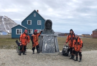 Figure 1. The research team (Kelly Mckeon, Julie Brigham-Grette, Xander Kirshen, Mark Goldner) in front of the Roald Amundsen statue in the cute little research station of Ny Ålesund. The team paid our respects to the stern-faced Amundsen every day! Photo courtesy of Mark Goldner.