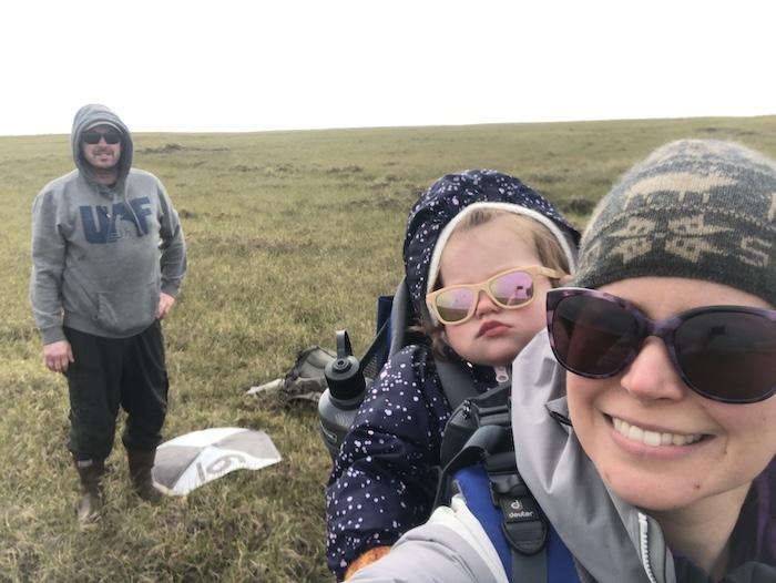Figure 1. University of Alaska Fairbanks (UAF) Research Assistant Professor Melissa Ward Jones (in front), Research Associate Professor Benjamin Jones (in back) and their daughter, then 14 months old and being carried in a carrier hiking backpack by Ward Jones to set up a series of ground control points for upcoming UAV surveys at the Teshekpuk Lake Observatory on Alaska's North Slope in August 2020. Photo courtesy of Melissa Ward Jones.