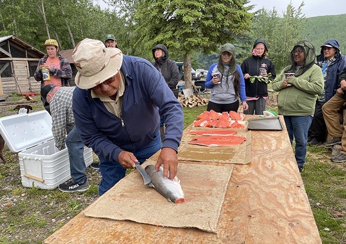 Figure 4. Max Taylor, a Hopi farmer, learns to filet fish at Nenana fish camp in June 2023. Photo courtesy of Noor Johnson.