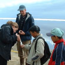 PolarTREC researcher Max Holmes collects water samples with the help of local Zhigansk students.